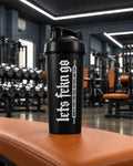 Black LETS FCKN GO protein shaker on an orange gym bench