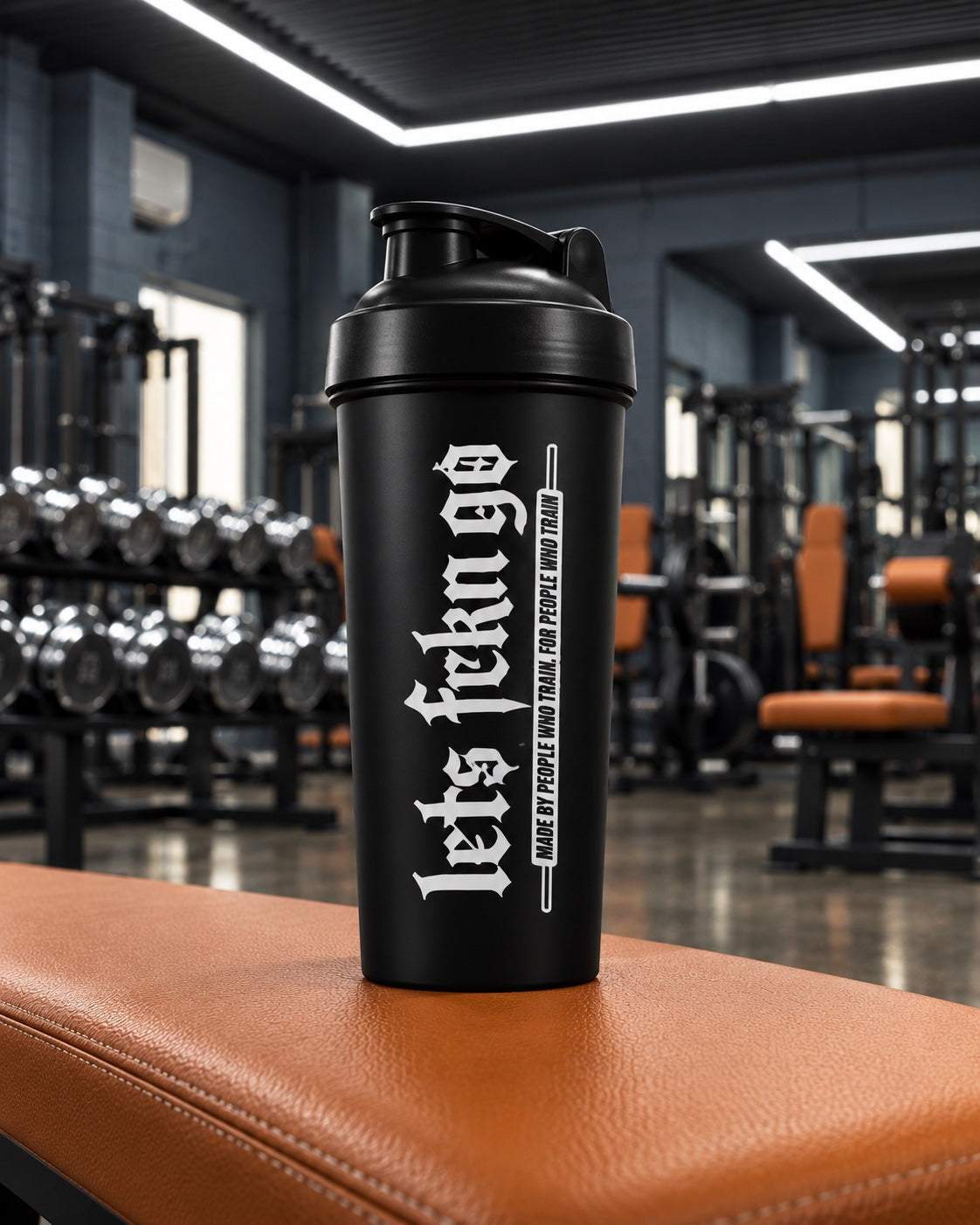 Black LETS FCKN GO protein shaker on an orange gym bench